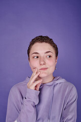 Fototapeta na wymiar Portrait of teenage girl with short hair posing against purple background