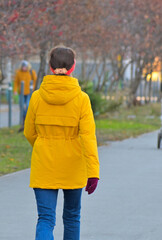 A woman walks along the sidewalk on an autumn day