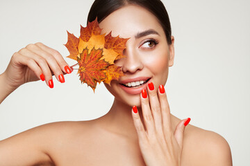 Portrait of beautiful young woman with autumn maple leafs. Healthy clean fresh skin natural make up beauty eyes and red nails