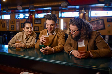 Friends having fun, talking drinking beer and using smartphone