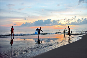 夕刻の海にサーファーのシルエットが浮かぶ海岸