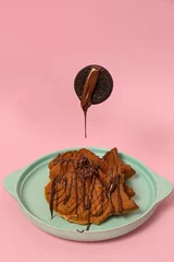 Gordijnen Vertical view of fish-shaped Taiyaki cones on a blue plate with chocolate syrup and a cookie on top © Nina Ljusic/Wirestock Creators