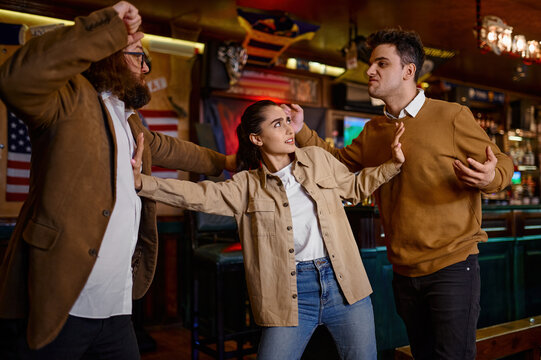 Woman trying to stop male friends fight at sport bar