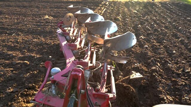 Reversible plough plowing ground in slow motion during golden hour in Latvia