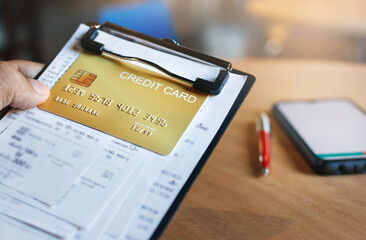 Close up view, hand holding cradit card with receipt on clamp board and mobile phone, Credit card debt and expenses paying concepts