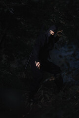 Fototapeta na wymiar Ninja silent killer waits in ambush in forest undergrowth