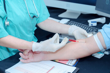 Doctor or nurse hand in white nitrile glove was using syringe to draw blood from patient's arm for taking a blood sample to examination and use a cotton swab moistened with alcohol to clean wound.