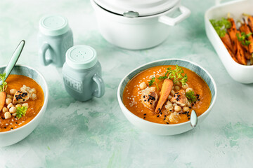 Pumpkin cream soup. Pumpkin and carrot puree soup with chickpeas and quinoa on a green background. Vegetarian cuisine. Vegan recipes.