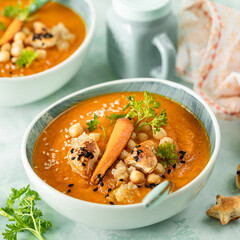 Pumpkin cream soup. Pumpkin and carrot puree soup with chickpeas and quinoa on a green background. Vegetarian cuisine. Vegan recipes.