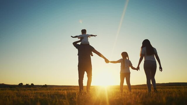 people in the park. happy family walking silhouette at sunset. mom dad and daughters walk holding hands in the park. happy family childhood dream concept. parents sun and children go back silhouette