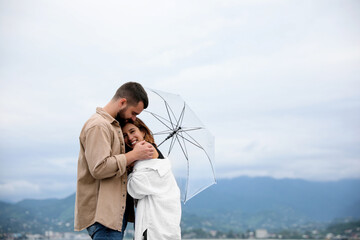 Young couple with umbrella enjoying time together under rain outdoors, space for text