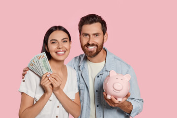 Happy couple with money and ceramic piggy bank on pale pink background