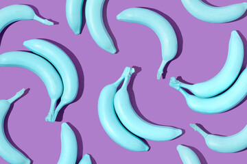 Creative pattern made with pastel blue bananas on bright purple background. 80s, 90s retro aesthetic style romantic concept. Minimal fashion surreal fruit idea.