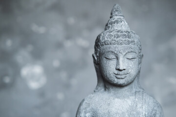Statue Buddha with closed eyes on grey stone background close up with copy space. meditation and spirituality background