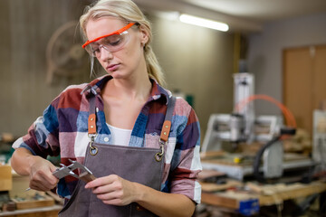 woman worker carpenter or craftsman using vernier calipers measuring dimensions of woodwork....