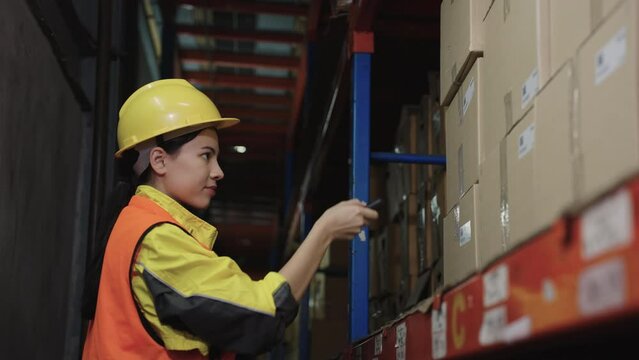 Beautiful woman using tablet and wireless bar code reader reading data on cardboard box on rack or shelf, Warehouse, Logistics, Import, Export, Shipping yard concept.