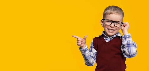 First time at school. Cute little child wearing glasses on yellow background, space for text. Banner design
