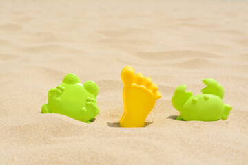 Fototapeta na wymiar Colorful plastic molds on sand, space for text. Beach toys