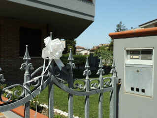 Metal fence with white bow on sunny day