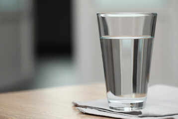 Glass of pure water on table against blurred background, space for text