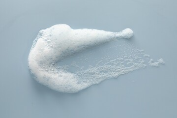 Smudge of white washing foam on color background, top view