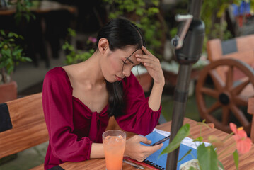 A trans lady wearing a puffed sleeves dress relaxes at a chic coffee shop early in the morning while scrolling through her social media on her phone.