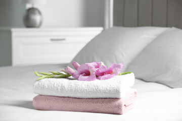 Terry towels with beautiful flower on bed indoors, space for text