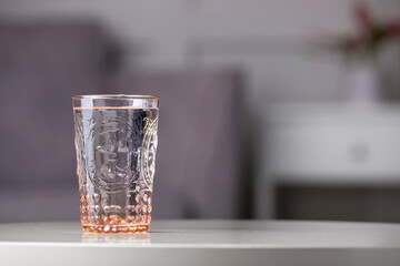 Glass of clean water on white table indoors, space for text