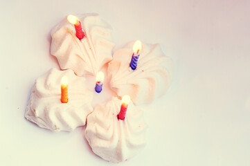Burning multi-colored holiday candles in white marshmallows on a colorful background of trend shades