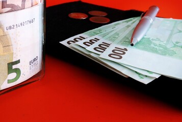 Saving jar bottle and notebook with cash Euro money on orange background - concept of money...
