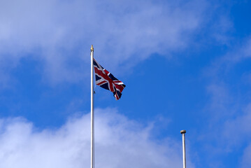 Flag of United Kingdom waving at famous City of Bath on a blue cloudy summer day. Photo taken August 2nd, 2022, Bath, United Kingdom.