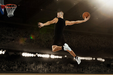 Slam dunk. Young professional basketball player playing basketball at basketball court with people fans. Photoreal 3d render of sport arena. © master1305