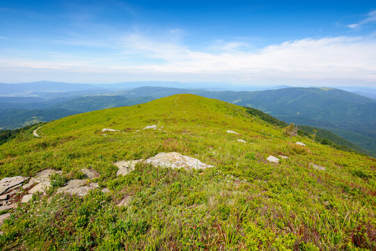 alpine scenery of carpathian mountains. stones on the grassy hills. sunny weather with clouds above the distant ridge