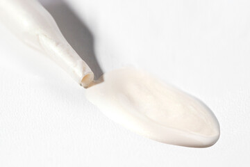 Cosmetic pipette with white pearl color smear on white background. Collagen, enzyme, ceramide and...
