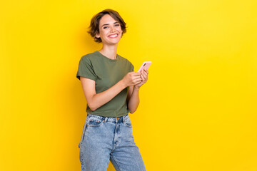 Photo of cheerful toothy girl with bob hairstyle wear khaki t-shirt writing message on smartphone...