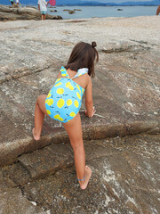 girl with swimsuit climbing on the rocks on the beach