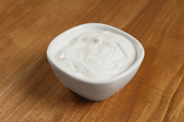 Bowl of tasty yogurt on wooden table