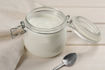 Jar of tasty organic yogurt on white wooden table