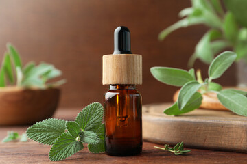 Bottle of essential oil and fresh herbs on wooden table