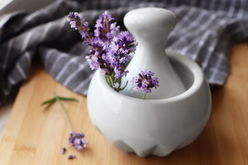 Obraz na płótnie Canvas Mortar with fresh lavender flowers and pestle on wooden table, closeup
