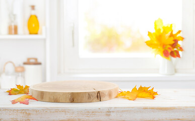 Wooden pedestal and faded autumn leaves on empty kitchen table