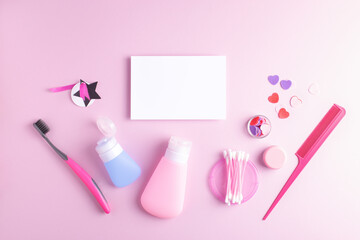 Teenage girl self care cosmetics and white paper card with blank space isolated on pastel pink background. Beauty, fashion, concept.