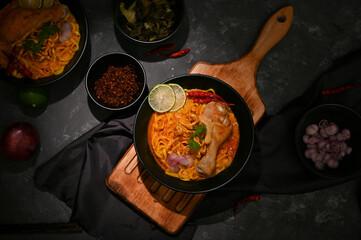 Top view of a tasty Thai curry egg noodles with chicken drumstick and vegetables