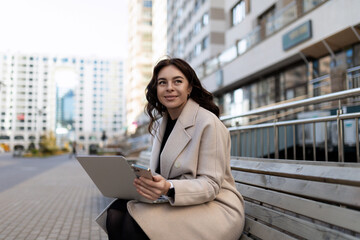 Business woman sitting with laptop outside the office, concept of successful business development