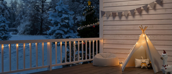 Home balcony or terrace on Christmas night decoration with teepee tent, toys, pouf, Christmas tree