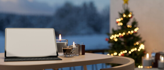 Tablet white screen mockup on the table over blurred background with Christmas tree.