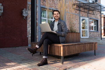 a young man sits on a bench with a laptop and looks away, principles and rules of successful business Concept