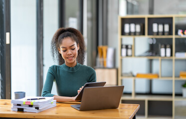 Fototapeta na wymiar Smiling African American businesswoman sitting on a laptop thinking happily analyzing data