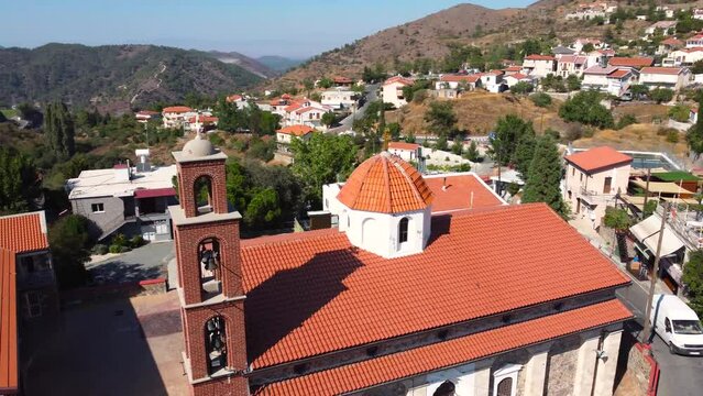 Aerial drone footage of traditional picturesque countryside hilltop village Farmakas, Nicosia, Cyprus. Close up 360 of christian church Saint Irene dome with ceramic tiled roof dome from above.