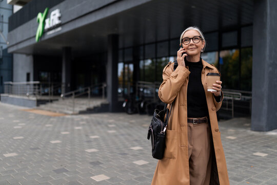 an Middle aged older business woman walks near the business center talking on a mobile phone, principles and rules of successful business Concept